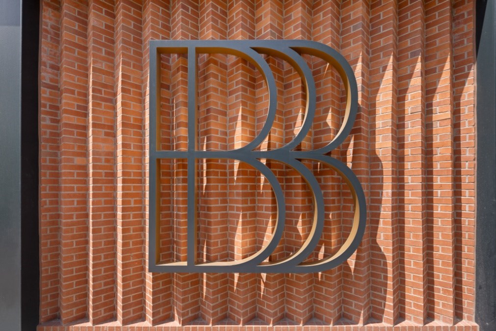 A large B is displayed on a brick wall.