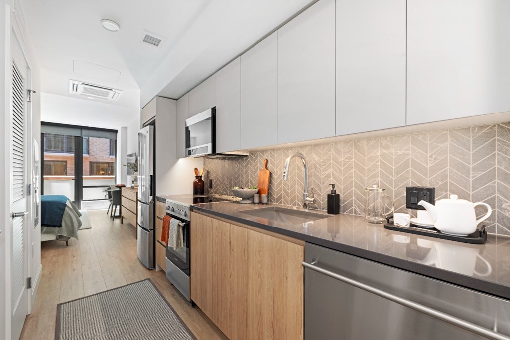 A modern kitchen with a stainless steel refrigerator and wooden cabinets.