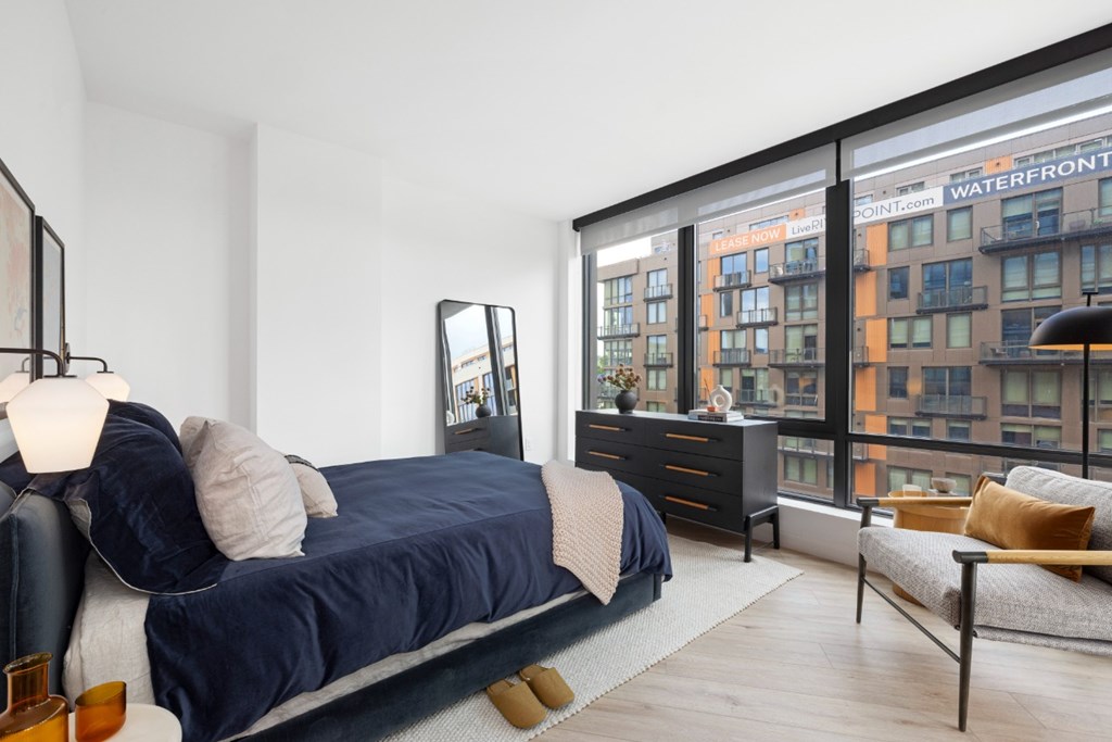A bedroom with a large bed and a view of a building with the sign "Waterfront" on it.