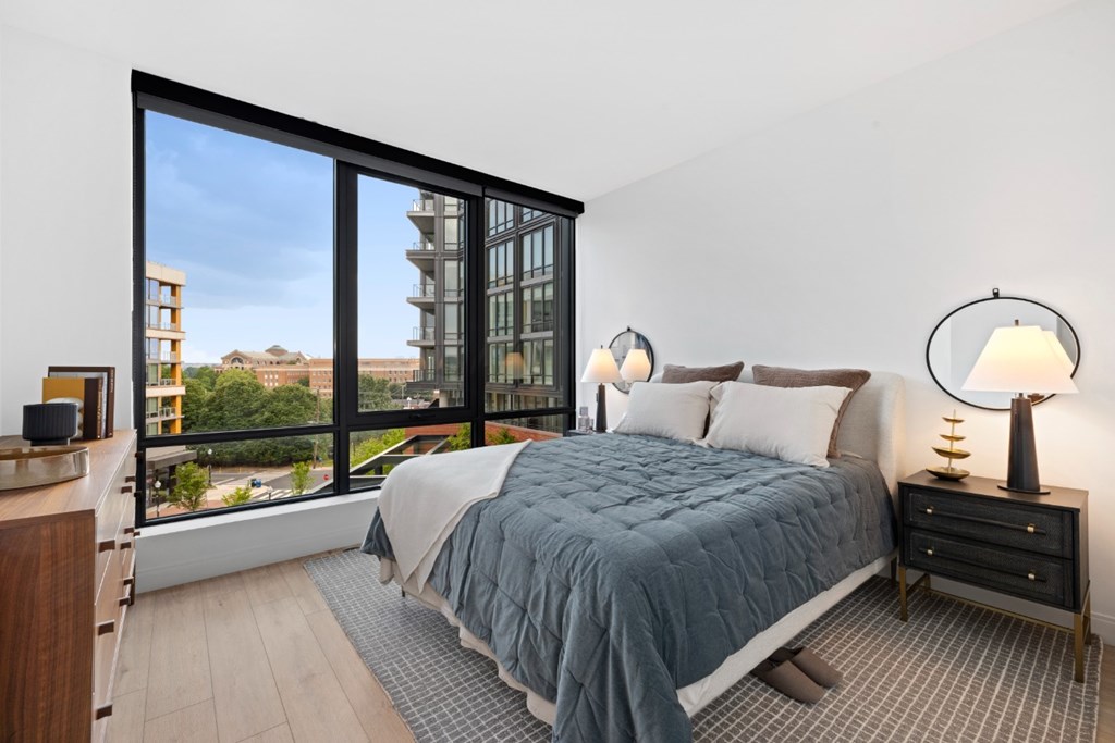 A bedroom with a large bed and a view of a cityscape through the window.