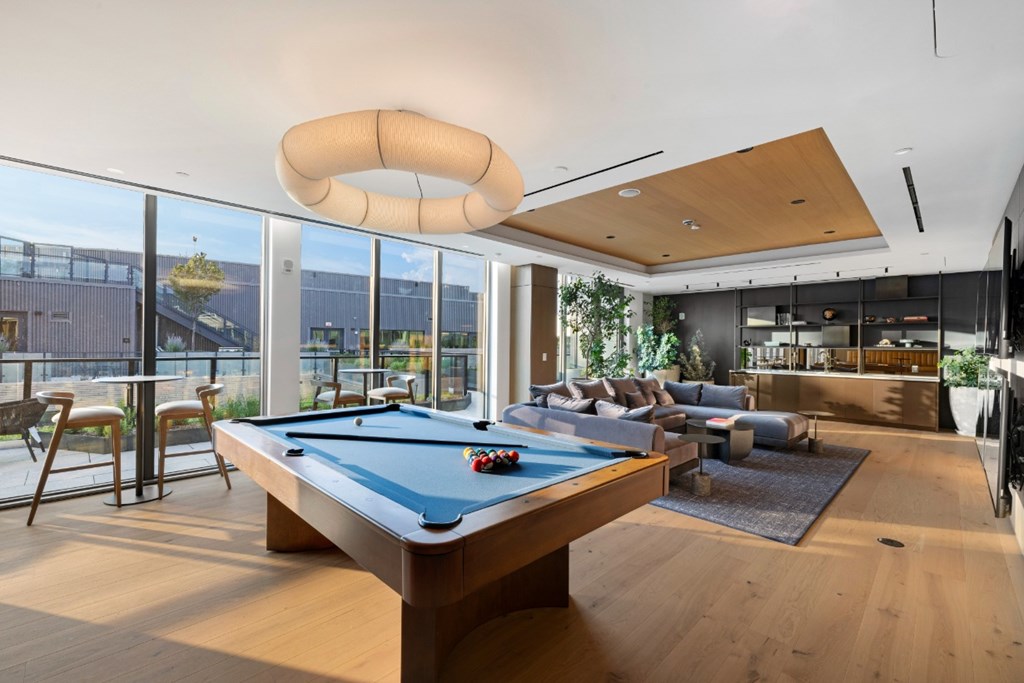 A pool table is in the middle of a room with a couch and a chair.