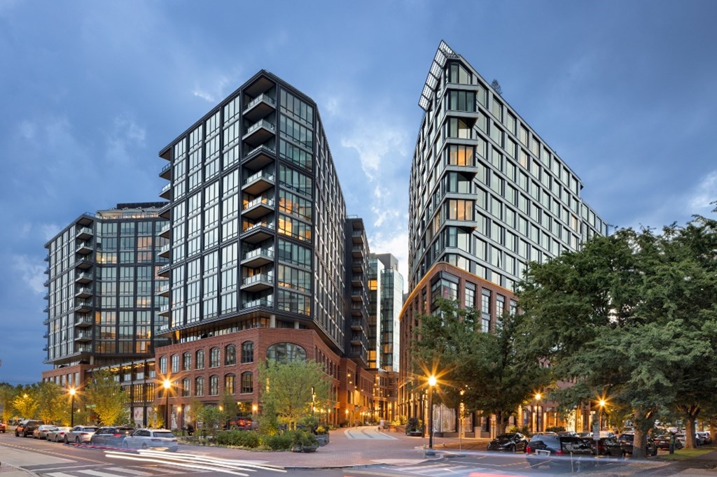 Two modern buildings are lit up at dusk.