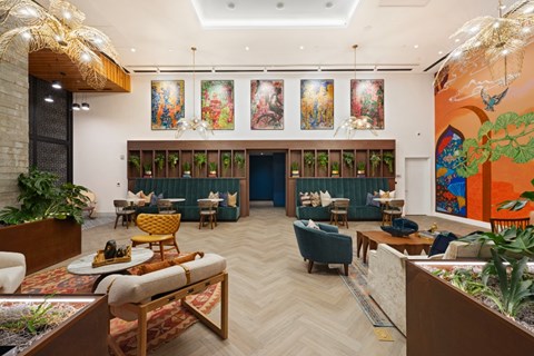 A room with a long table and chairs, a couch, and a large mural on the wall.