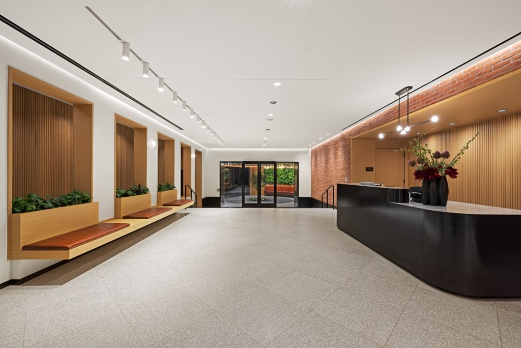 A long hallway with a black reception desk and wooden planters on the side.