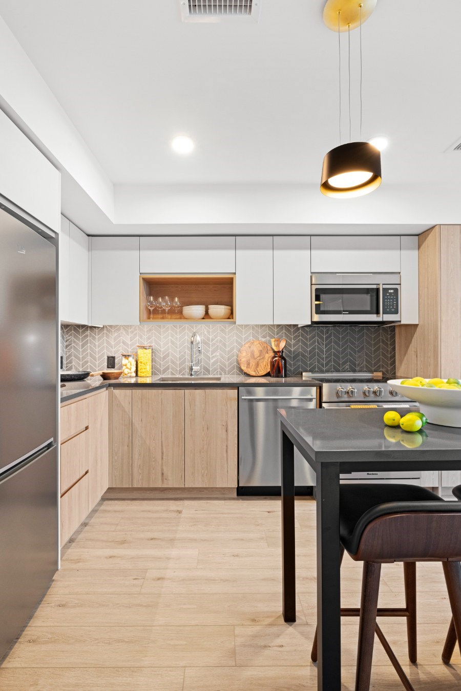 A modern kitchen with a black countertop and wooden flooring.
