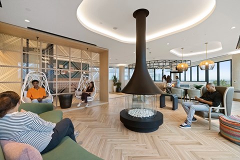 A man in an orange shirt is sitting in a modern lounge area.