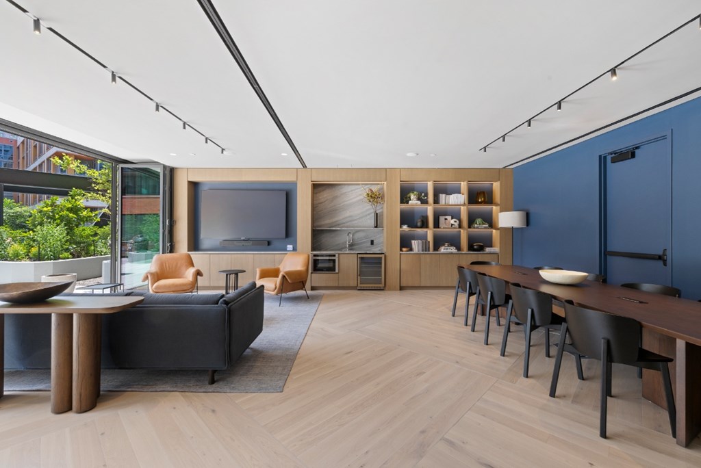 A modern living room with a black couch, wooden furniture, and a large window.