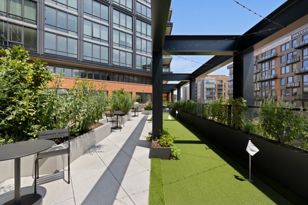 A patio with a table and chairs is surrounded by plants and buildings.