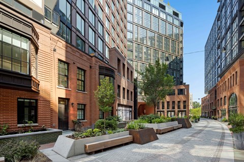 A long brick building with a lot of windows and a tree in front.
