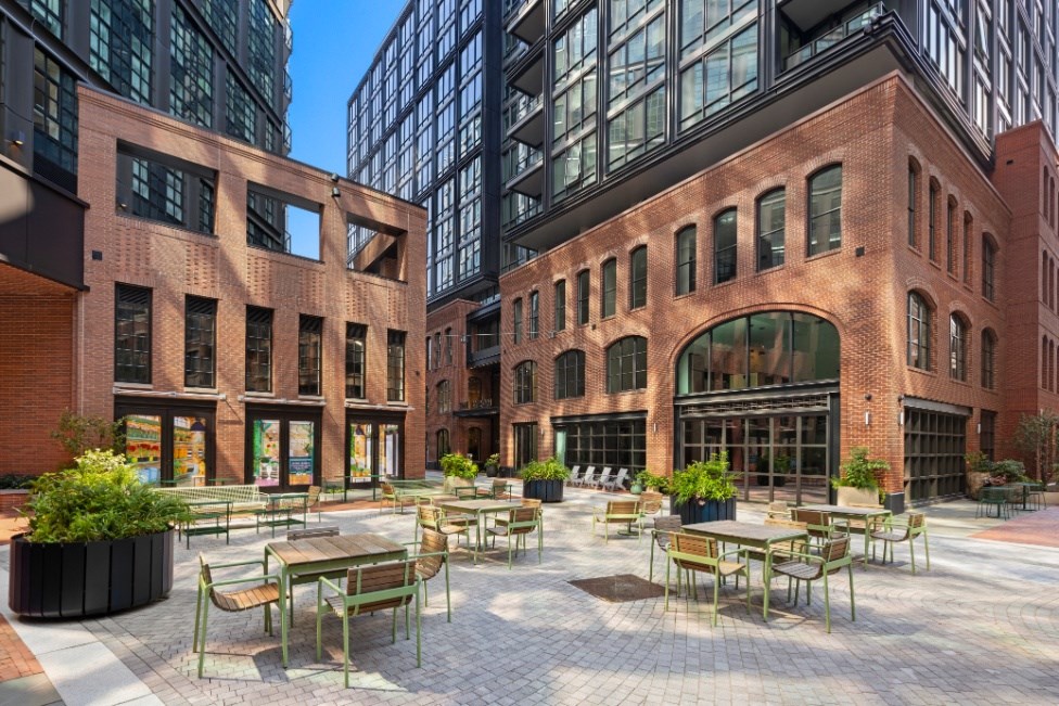 A courtyard with tables and chairs surrounded by buildings.