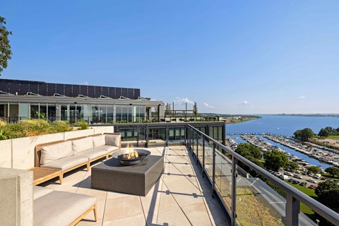 A patio with a fire pit and a view of a marina.