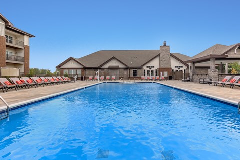 A large swimming pool in front of a building with a clear blue sky.