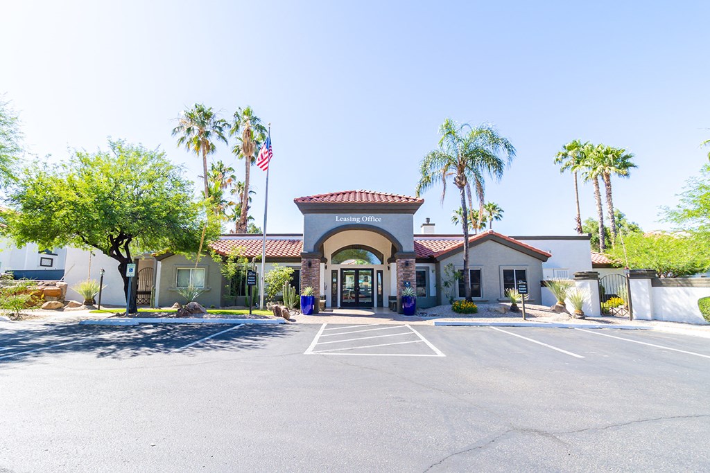 a parking lot with a building and palm trees in the background
