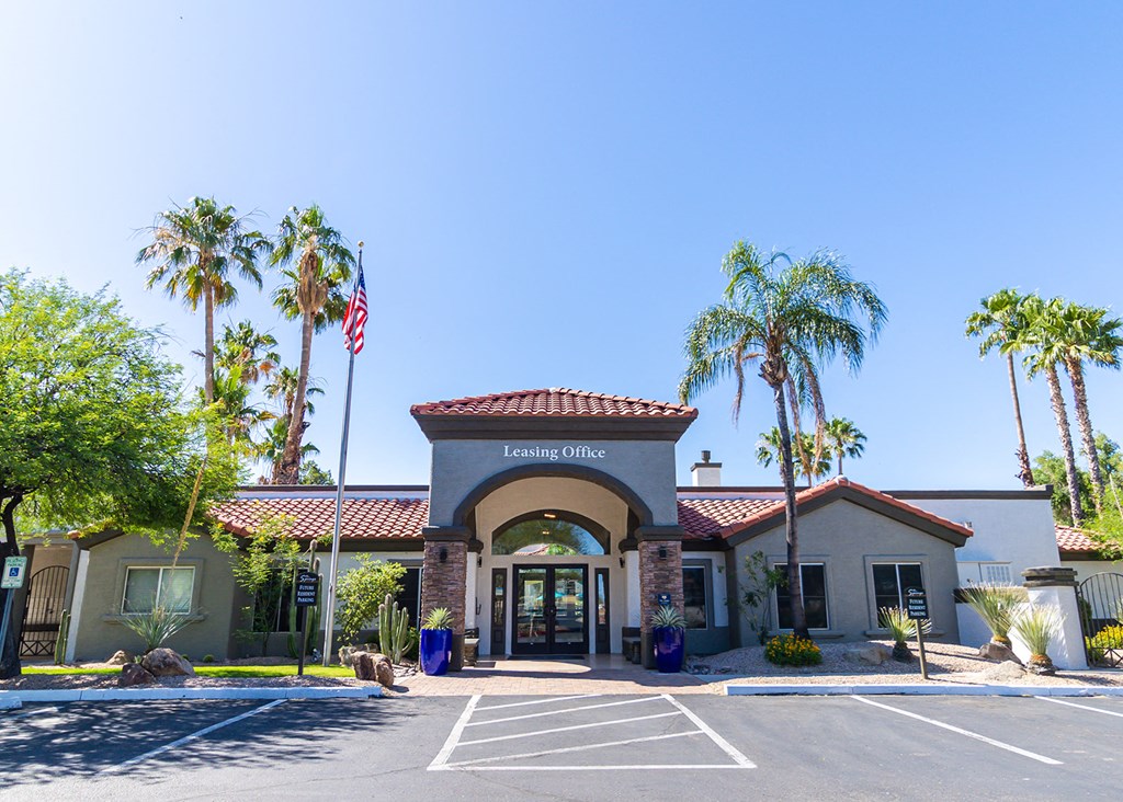 a building with the leasing office on the side and a parking lot in front of it