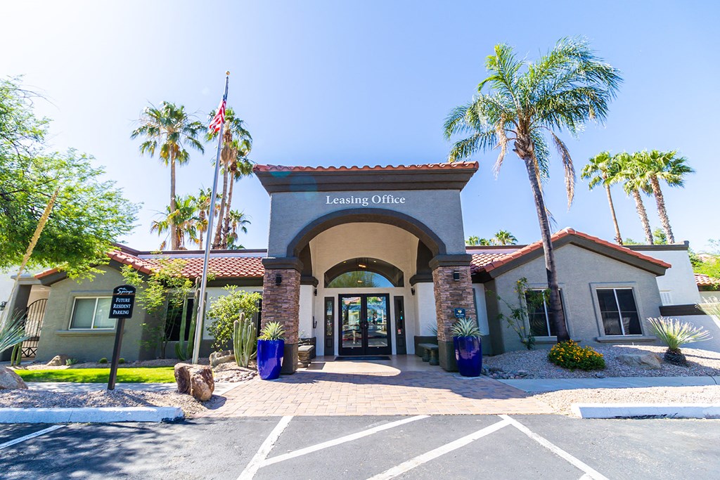 a building with a sign that reads leasing office in front of a palm tree