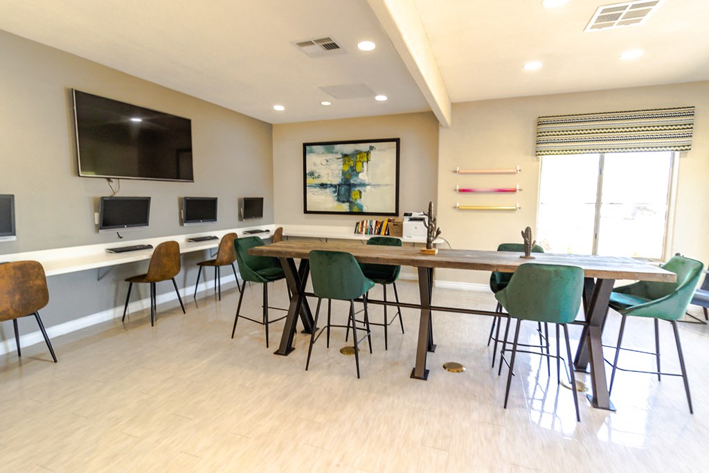 a room with a long table with chairs and a television on the wall
