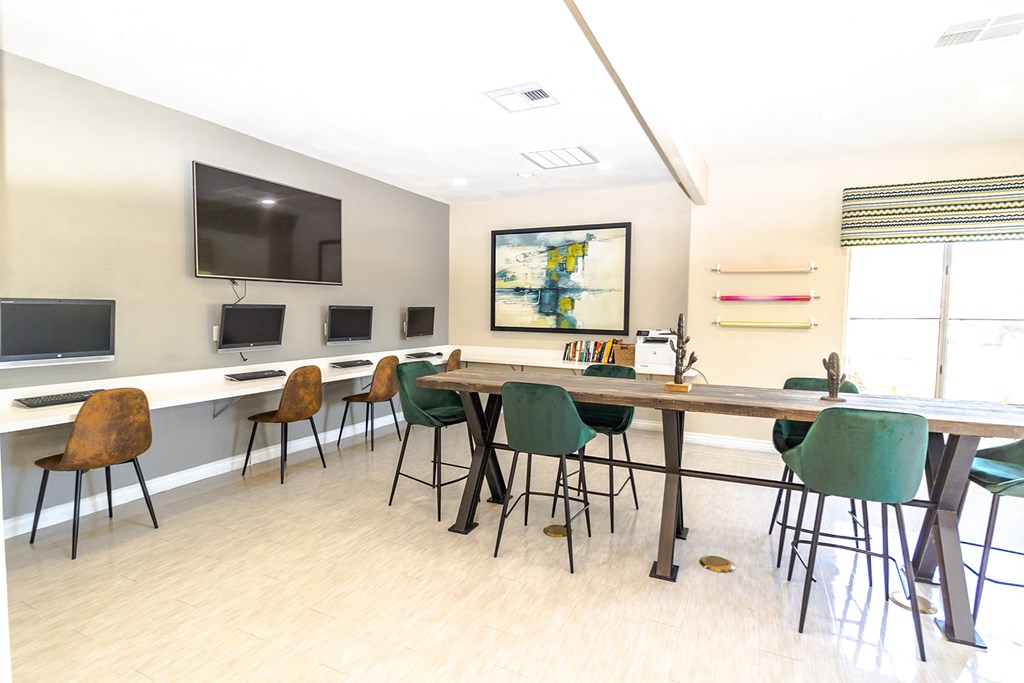 a room with a long table with chairs and a television on the wall