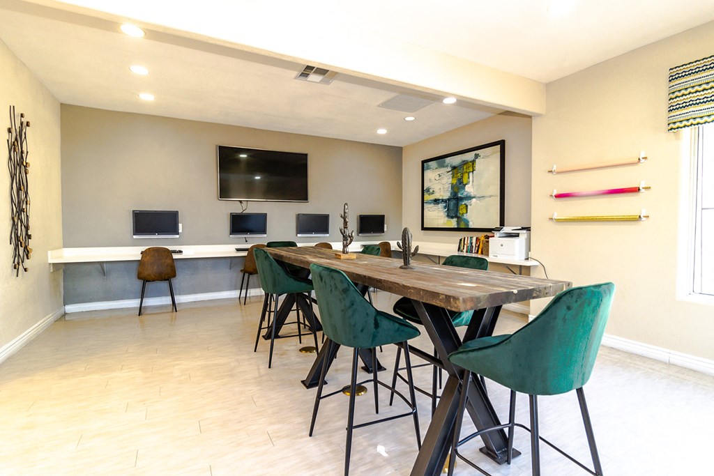 a room with a long wooden table with green chairs and a flat screen tv on the wall