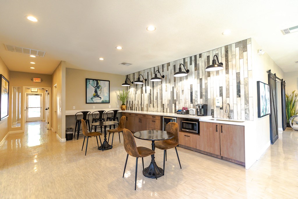 a dining area with a table and chairs and a counter with a microwave and coffee maker
