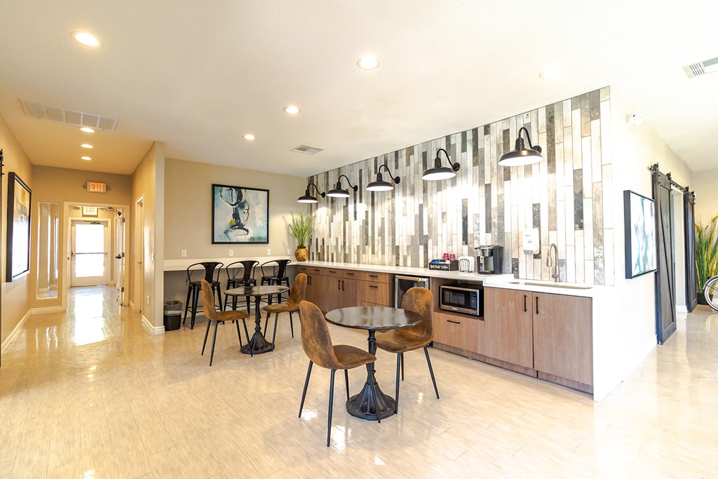 a lounge area with a table and chairs and a counter with a microwave and coffee maker