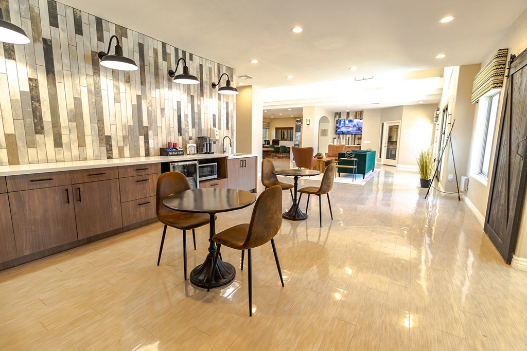 a dining area with tables and chairs and a kitchen with a television in the background