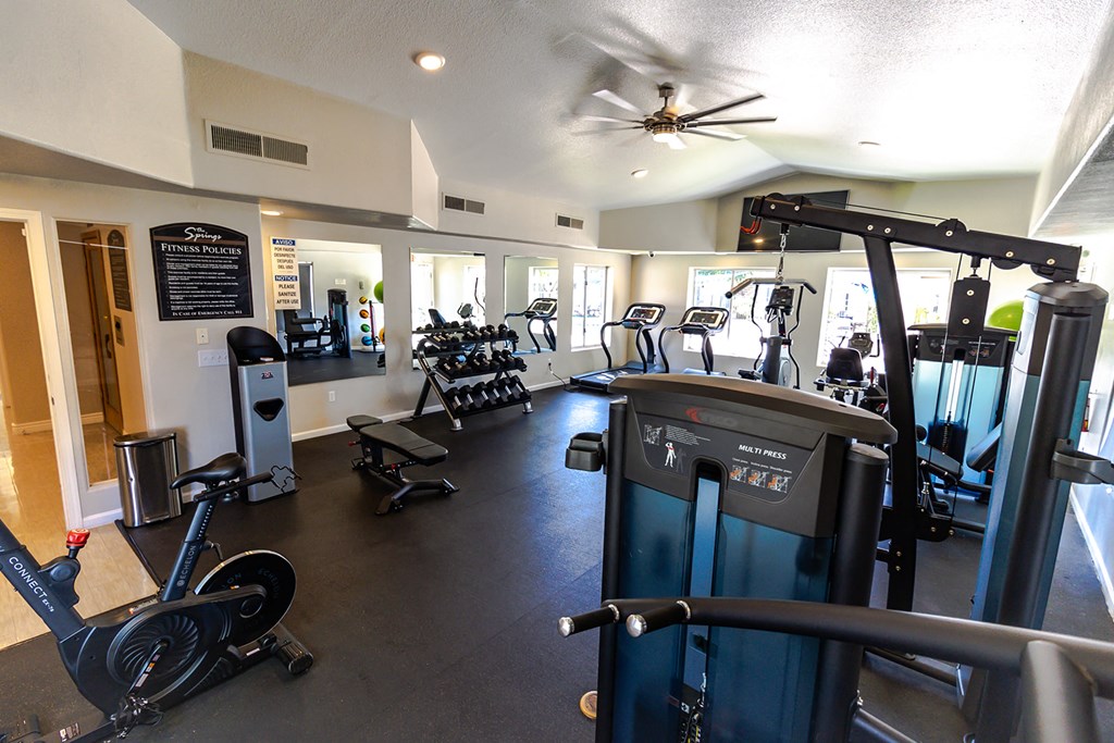 a spacious fitness room with cardio equipment and weights