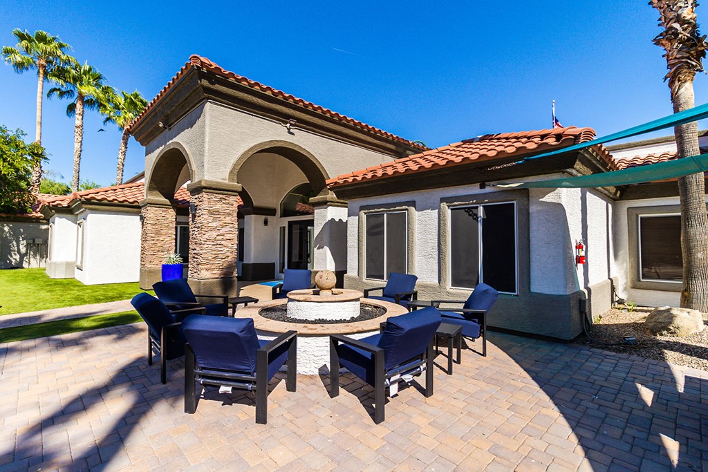 a patio with a fire pit and blue chairs