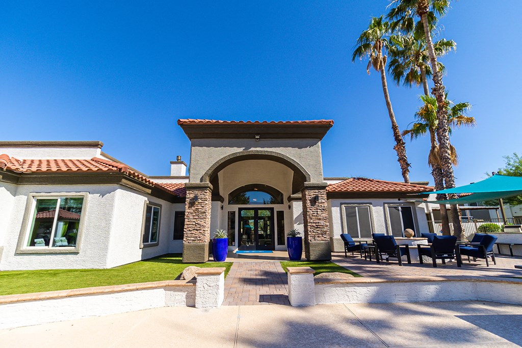 a picture of the front of the clubhouse with a blue sky and palm trees in the background
