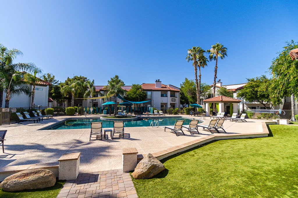 a large swimming pool with lounge chairs and umbrellas