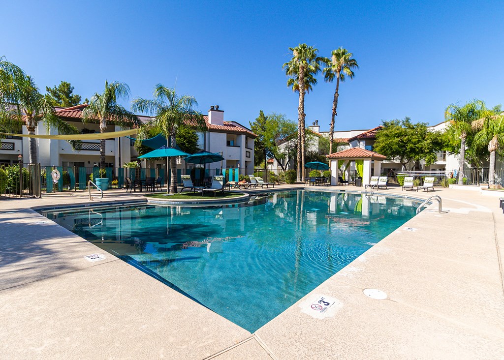 a large swimming pool with palm trees in the background
