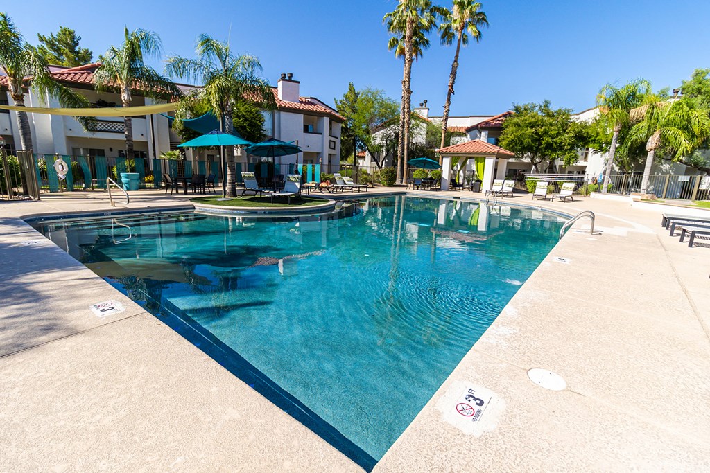 a large swimming pool with umbrellas and buildings in the background