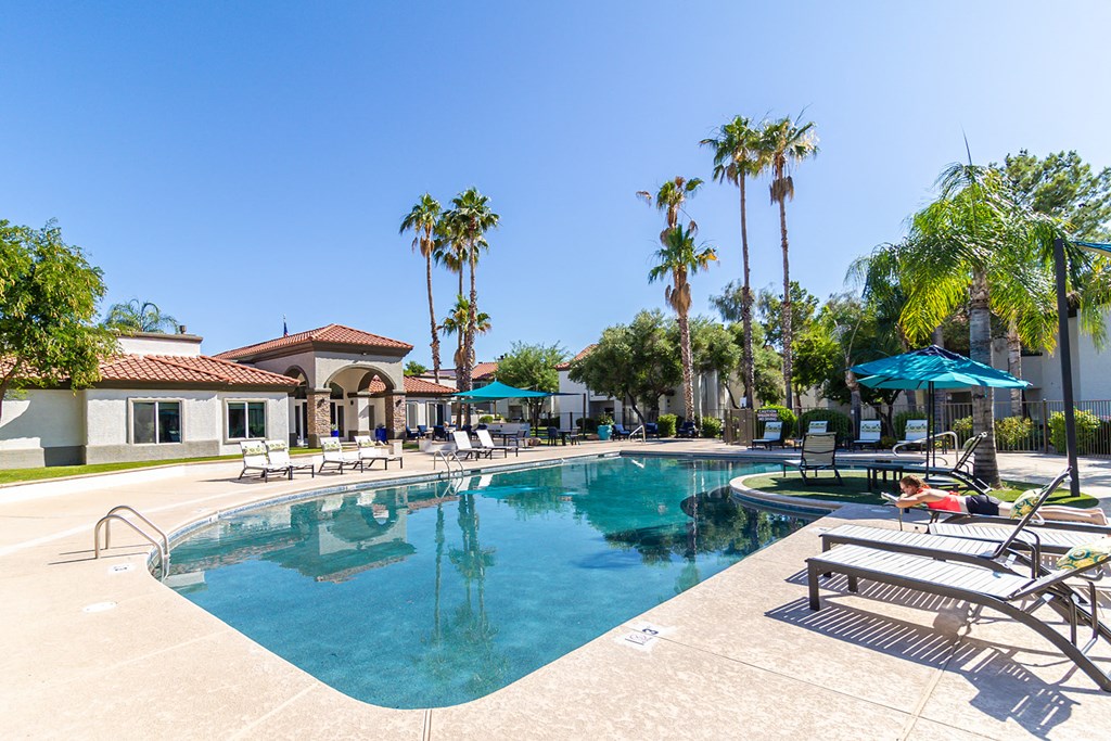 a large swimming pool with lounge chairs and umbrellas