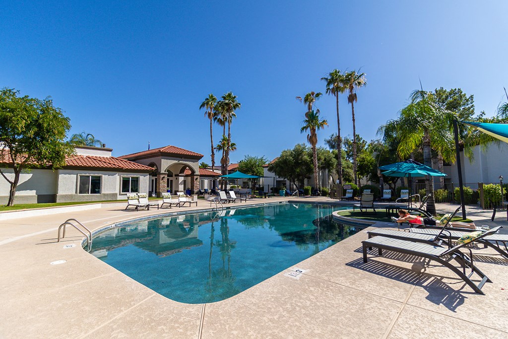 a large swimming pool with lounge chairs and umbrellas