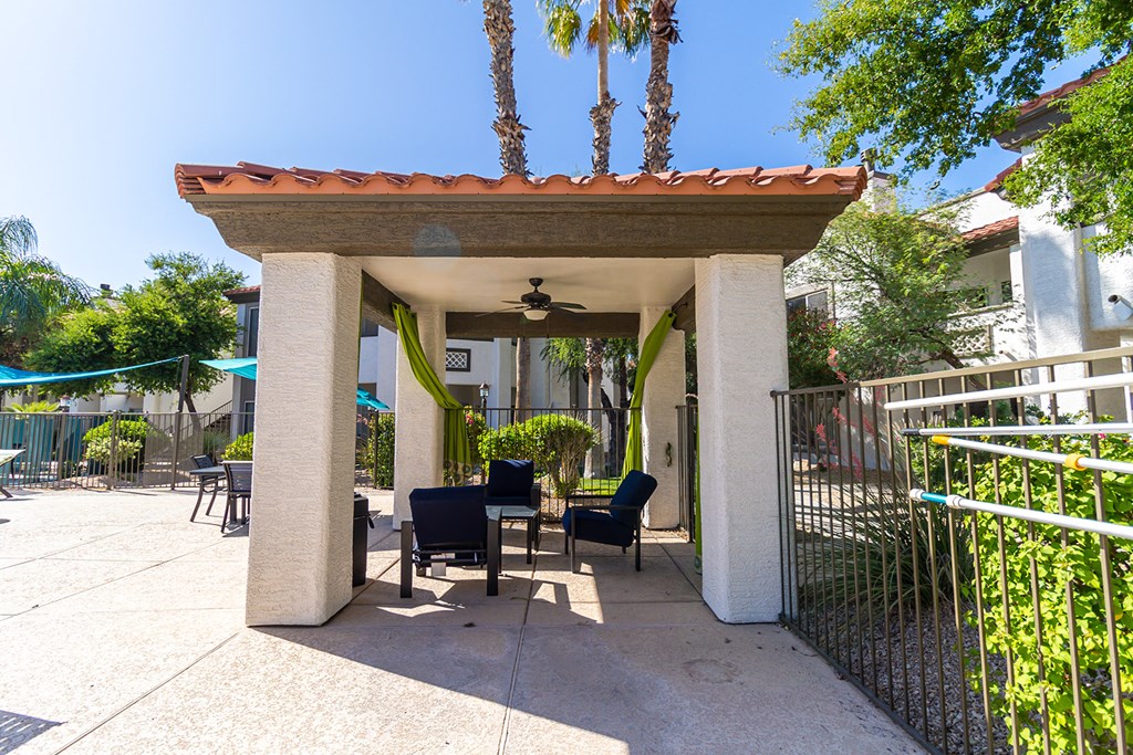 a pergola with a table and chairs in front of a house