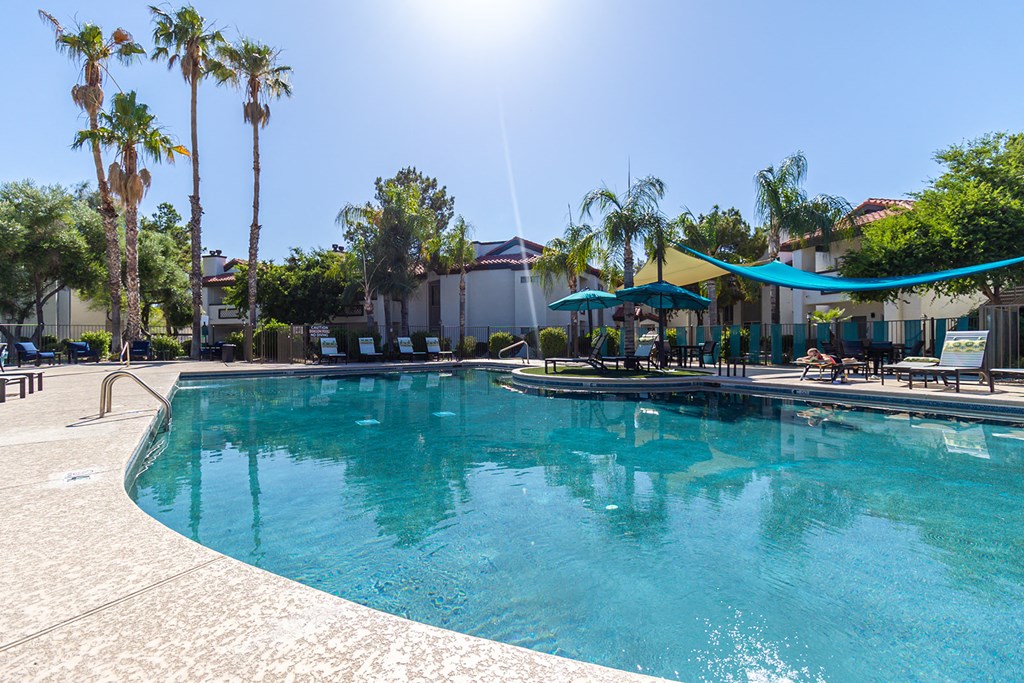 a large swimming pool with lounge chairs and umbrellas