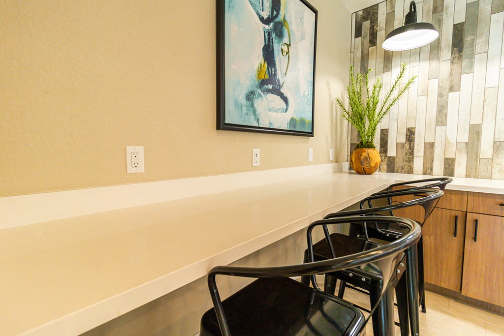 a long counter with black chairs and a pendant light