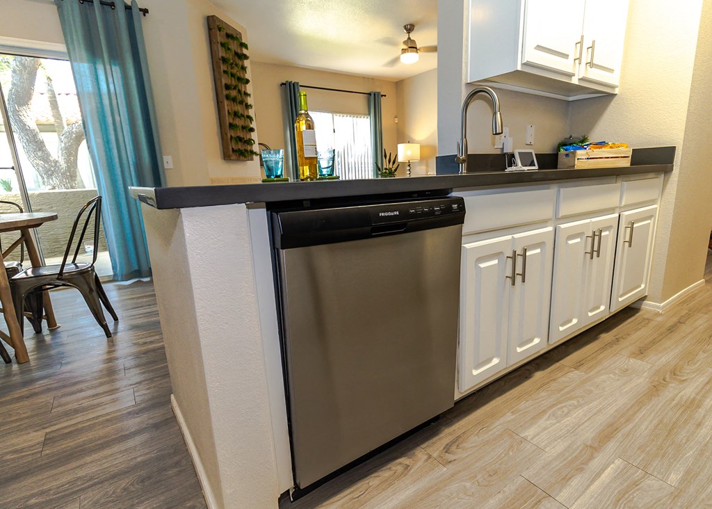 a kitchen with white cabinets and a stainless steel dishwasher