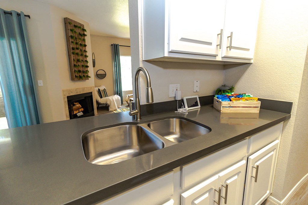 a kitchen with white cabinets and a stainless steel sink