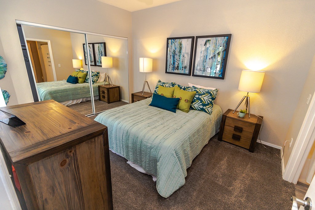 a bedroom with a large mirror and a bed with a blue comforter