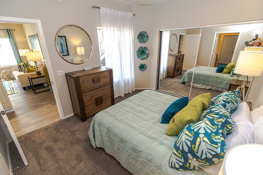 a bedroom with a large bed with green and blue pillows