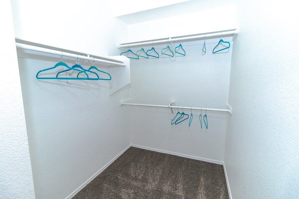 a small walk in closet with white walls and a gray carpet