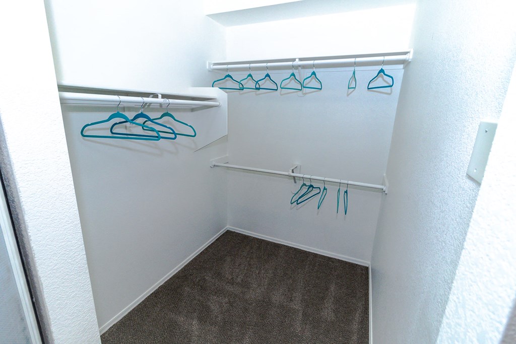 a walk in closet in a small room with clothes hanging on the racks