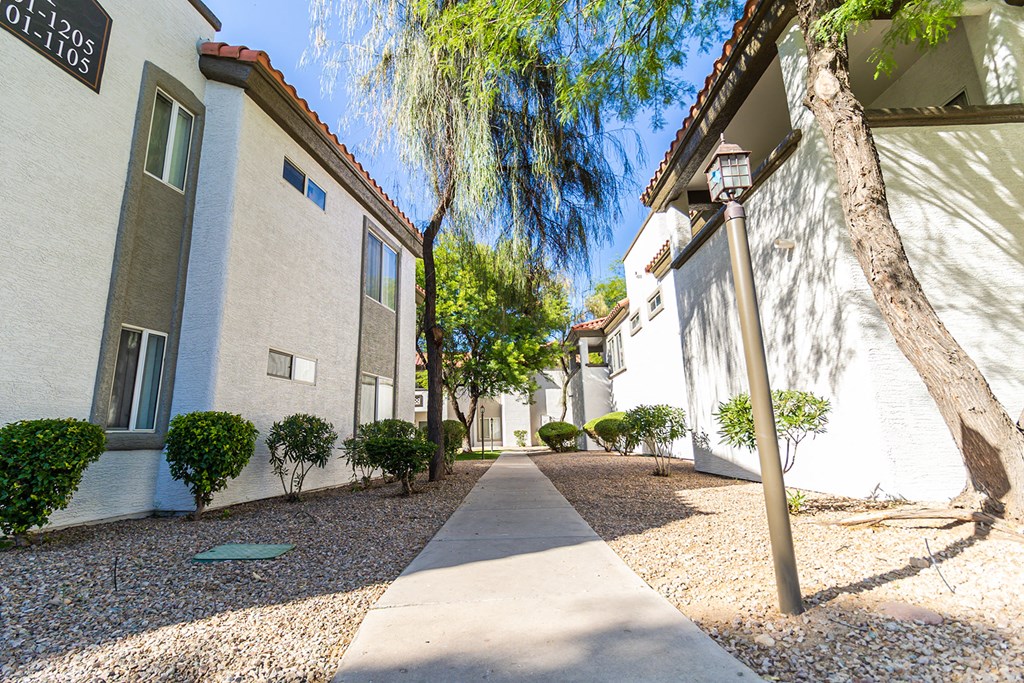 a walkway between two buildings at the whispering winds apartments in pearland, tx