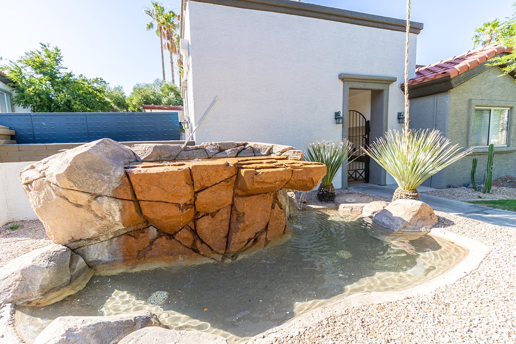 a fountain in a backyard with a house in the background