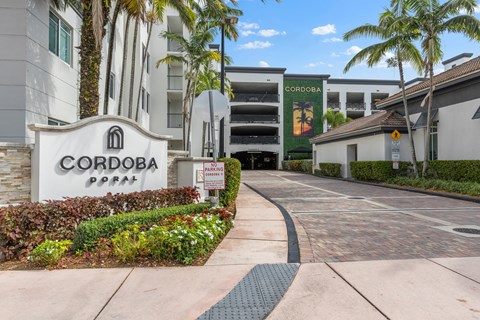 The image shows the entrance to the Cordoba Apartments with a sign and a well-maintained garden.