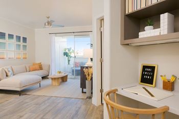 A living room with a white couch, a wooden chair, and a white desk with a sign that says "Home Sweet Home".