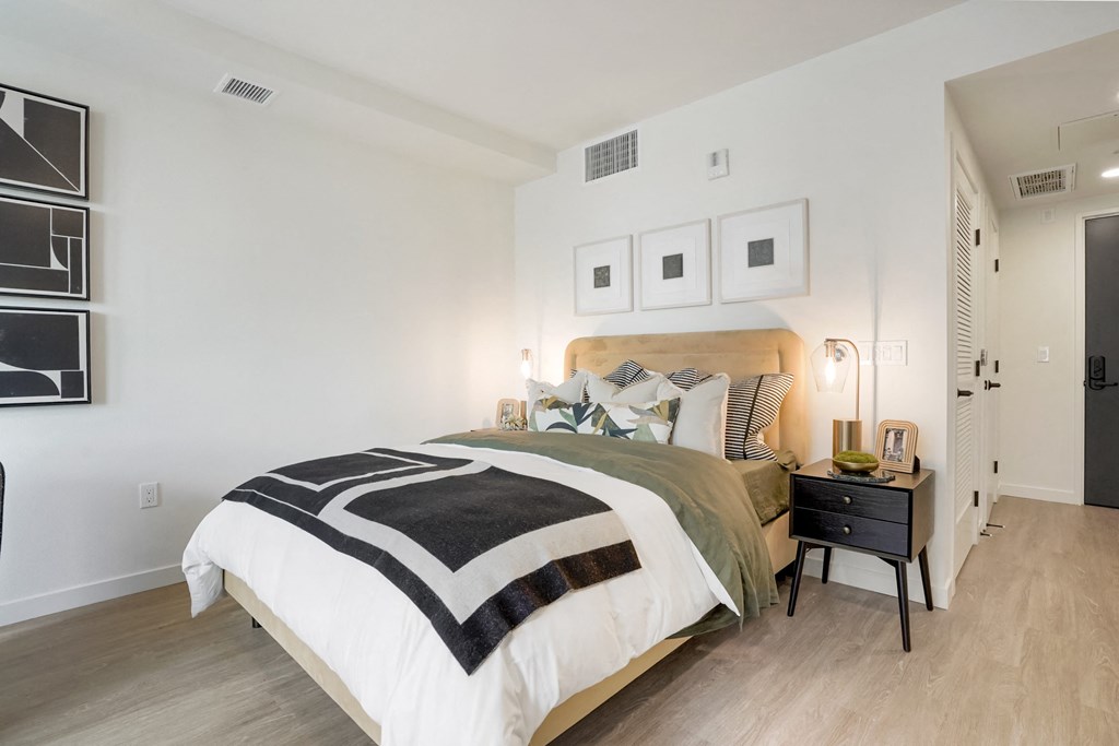 a bedroom with white walls and a bed with black and white pillows