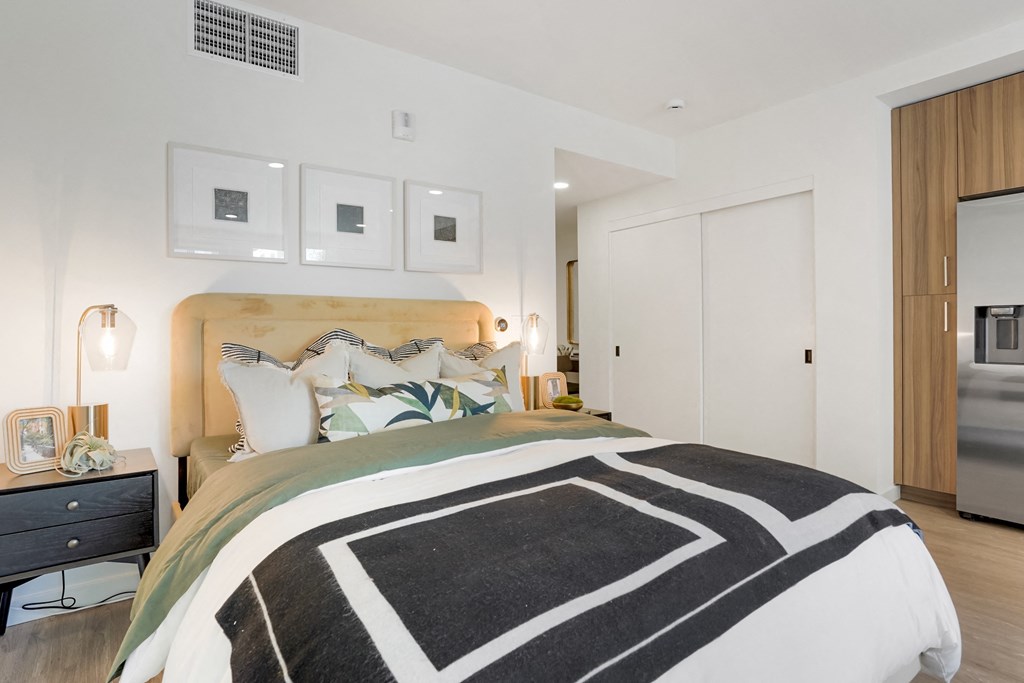a bedroom with white walls and a bed with black and white pillows