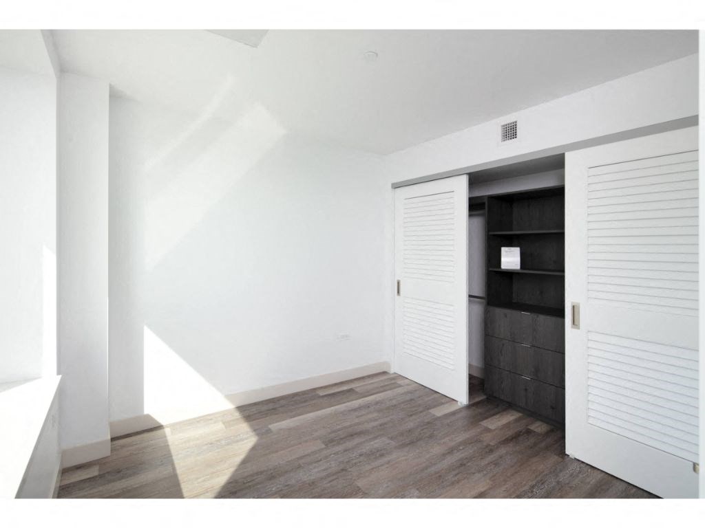 Apartments For Rent In SOMA - Bedroom With High Ceilings, Large Closets, Luxury Vinyl Flooring, And A Window With City Views.