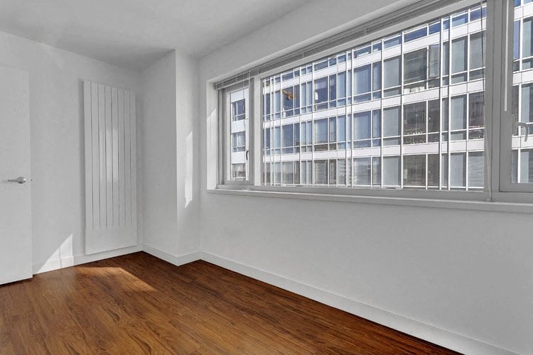 a bedroom with a large window and hardwood floors
